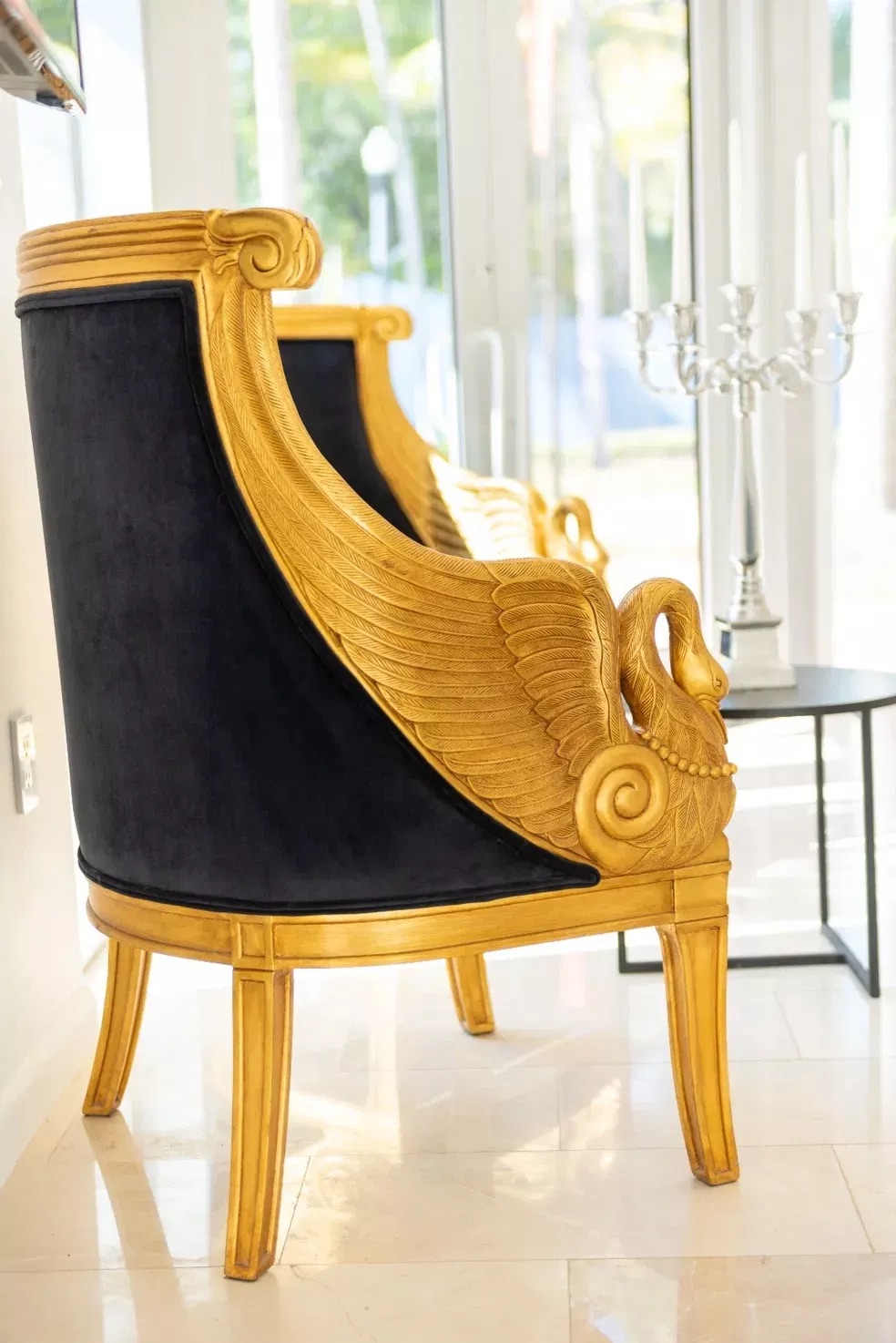 A luxurious gold-trimmed chair with blue upholstery, set against a white wall.