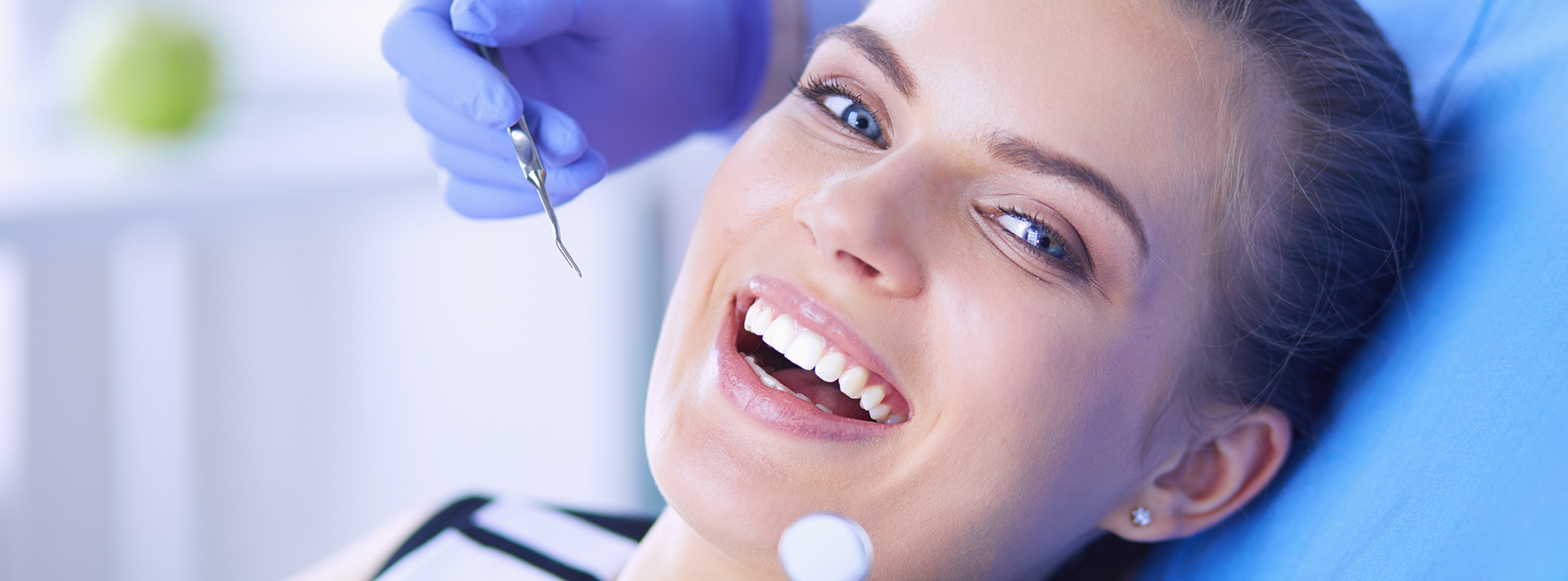 A woman receiving dental treatment, with a dentist s hand visible holding a dental tool.