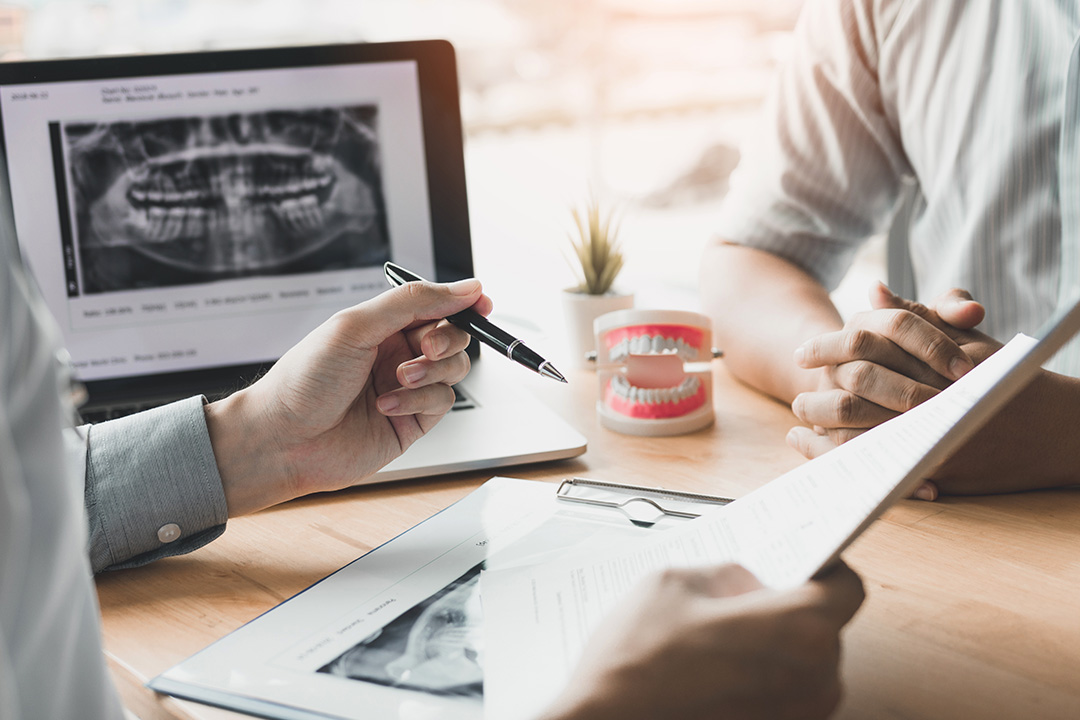 A split-screen image showing a dental consultation on one side with a patient s mouth displayed on a screen, and on the other side, a professional interaction where a person is signing papers while another individual takes notes.