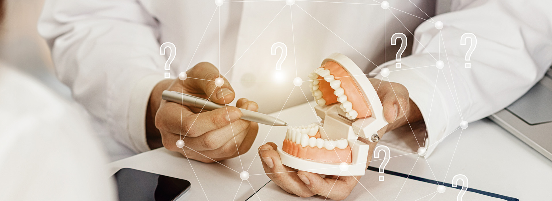 An image of a dental professional holding an open mouth model, with a focus on the teeth and gums, set against a digital interface displaying various dental tools and symbols.