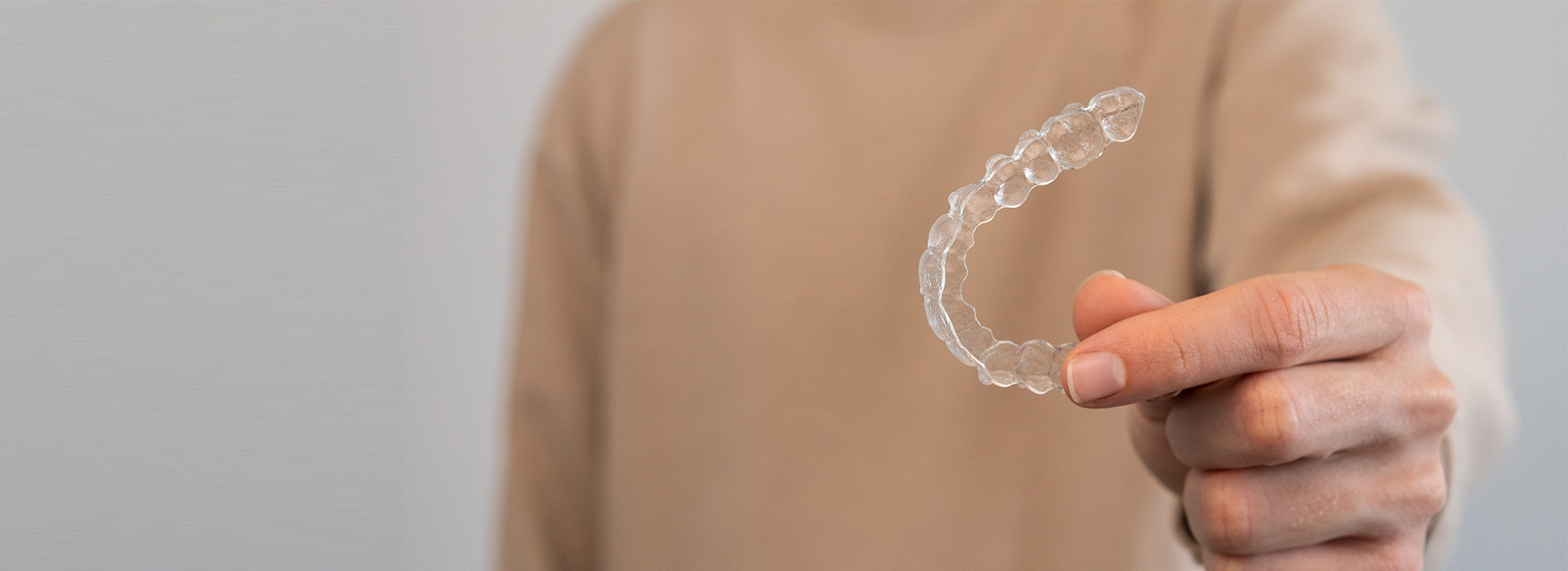 A hand holding a bubble with a transparent surface, against a blurred background.