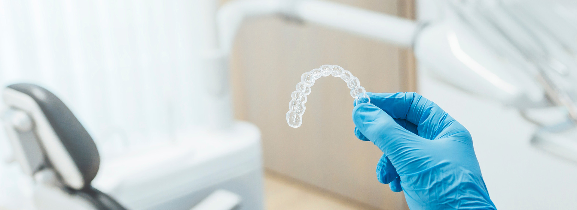 The image shows a transparent dental impression being held by a person wearing blue gloves, with the impression placed on what appears to be a countertop or table in a clinical setting.