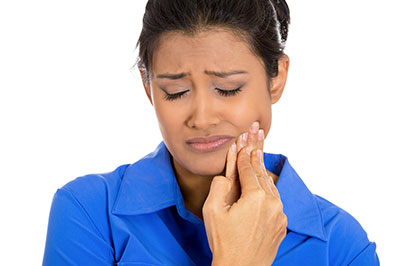 A woman in a blue shirt with her mouth open, wearing a ring on her finger, and looking upwards.