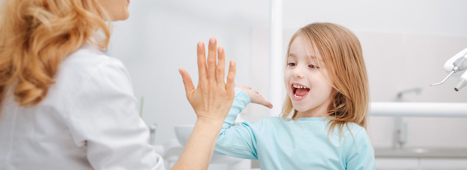 A woman and a young girl interacting in a bathroom, with the child being assisted by the adult.